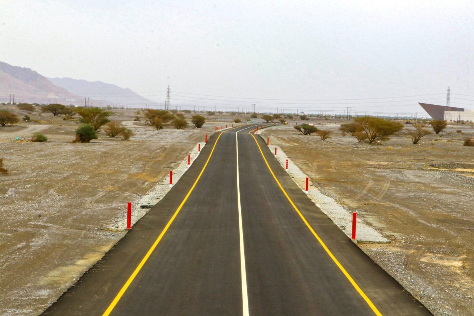 The new link road curving through open terrain with marker posts along both shoulders